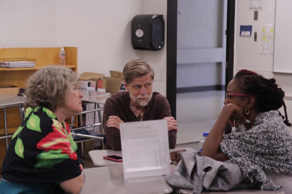 Three people sitting at desks in conversation