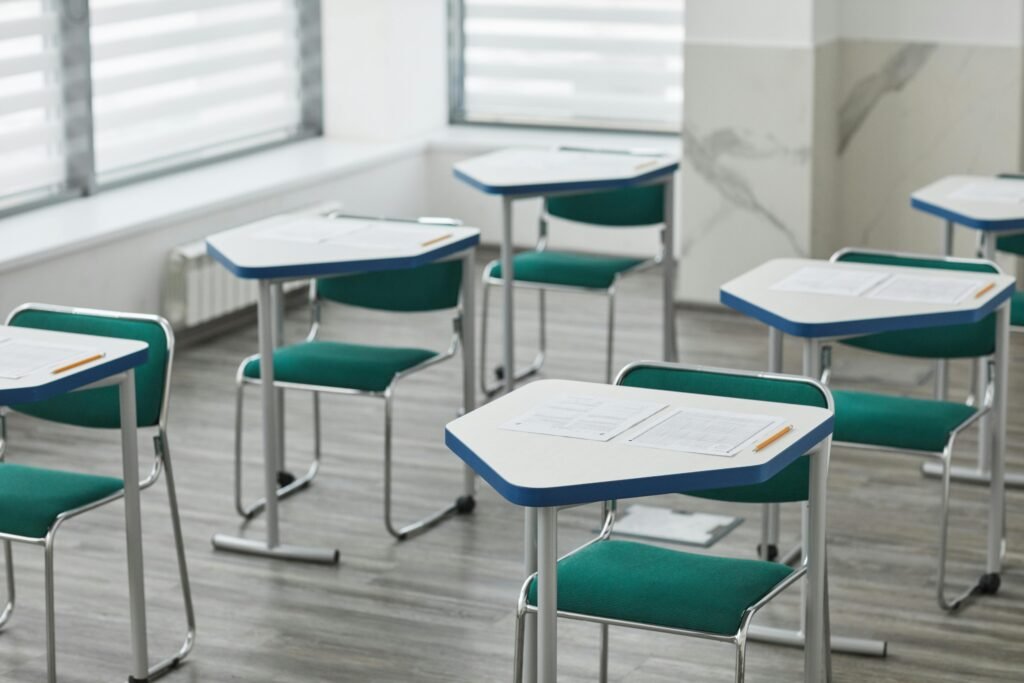 An empty classroom with arranged desks, exam papers, and pencils ready for students. Social entrepreneurship can be used by educators in the classroom to build agency in children.